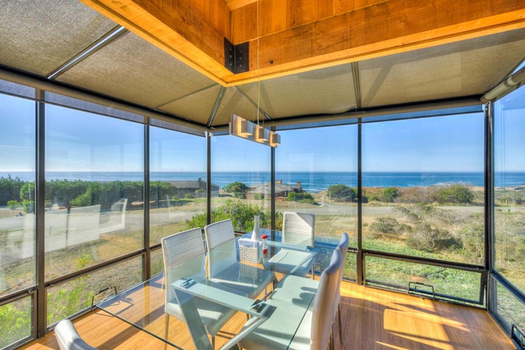a dining room with a table and chairs and large windows at Breakers Retreat in Sea Ranch
