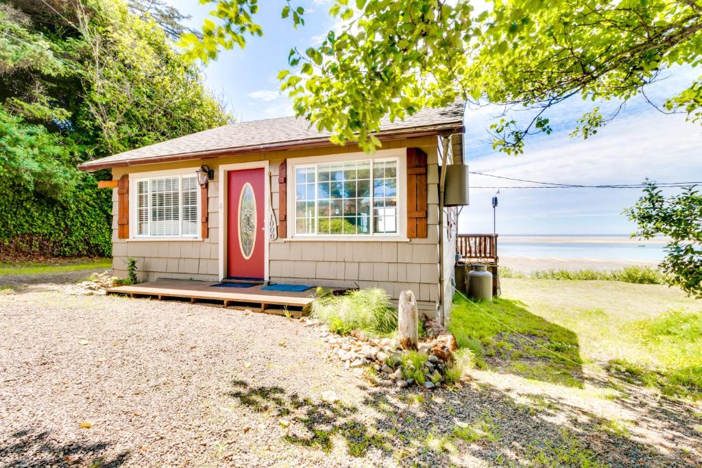 een klein huis met een rode deur op een oprit bij Happy Camp Beachfront Cabin in Netarts