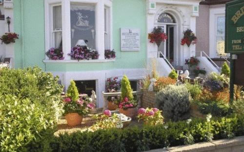 een huis met bloemen en planten ervoor bij Britannia Guest House in Llandudno