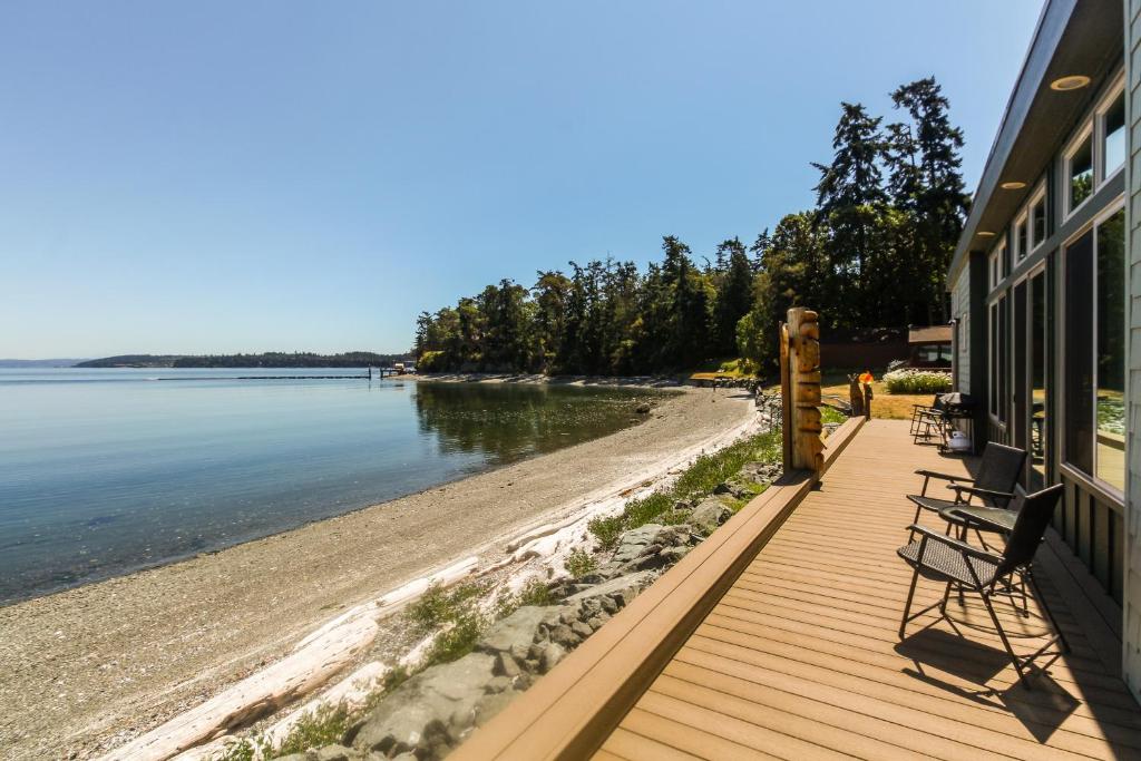 a wooden deck with benches on a beach at Wonder House in Coveland