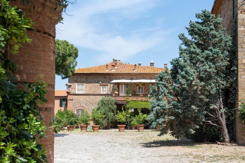 un grande edificio in mattoni con un albero di fronte di Fattoria Pian Di Rocca a Castiglione della Pescaia