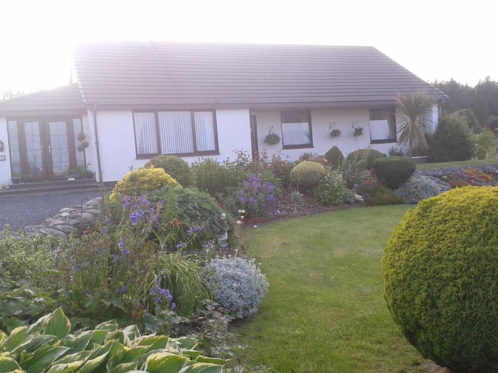 a white house with a garden in front of it at Mo-Dhachaidh B&B in Poolewe