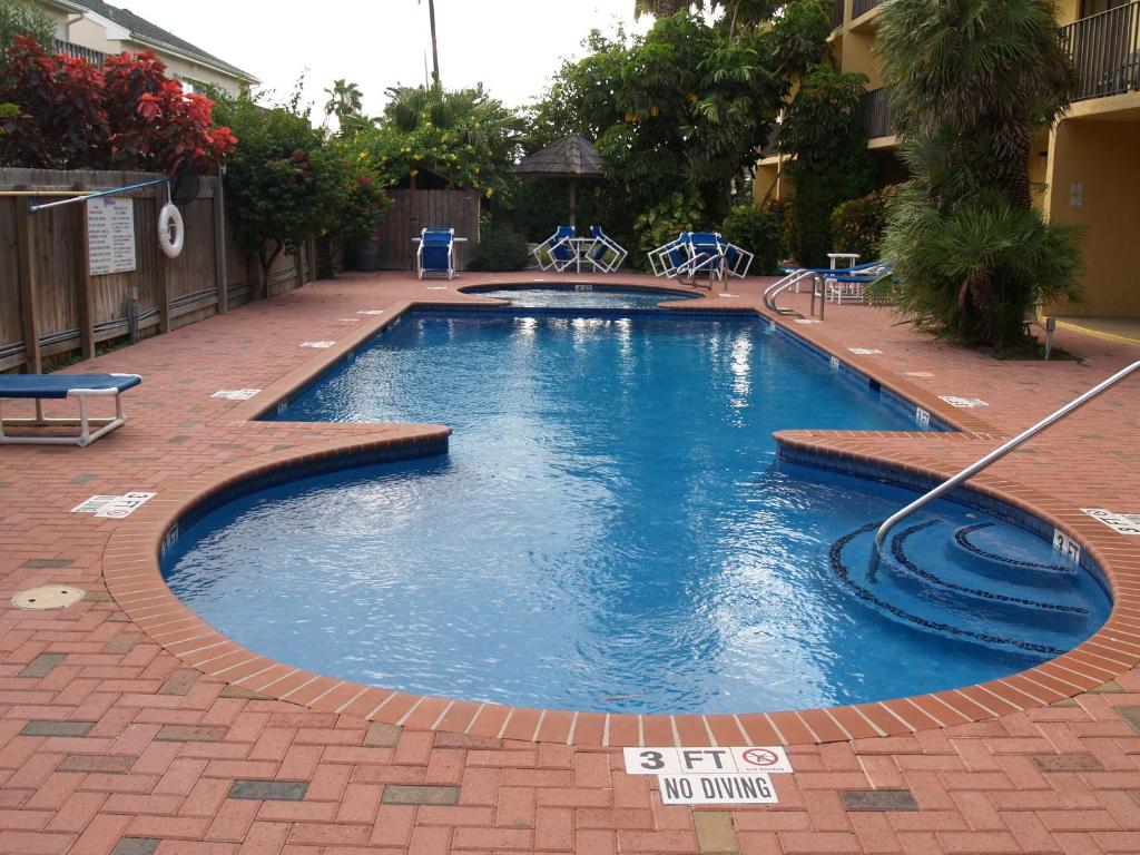 a large swimming pool in a courtyard with a brick floor at Ventura in South Padre Island