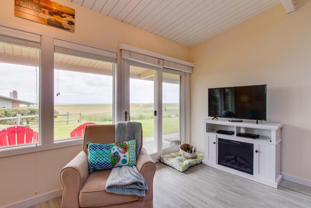 a living room with a tv and a chair and a fireplace at Surfside Suite On The Sea, Too in Gearhart