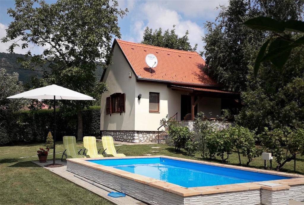 a swimming pool in front of a small house at Cseresznyevirág Vendégházak in Kővágószőlős