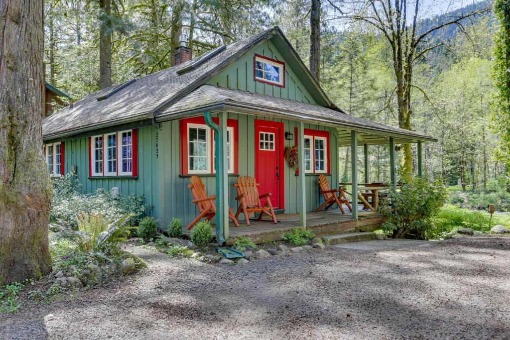 uma pequena casa verde e vermelha na floresta em The Cozy Cabin em Welches