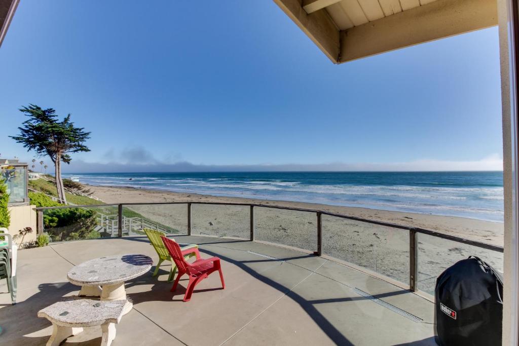 Un patio con mesa y sillas y la playa. en Vintage Views, en Cayucos