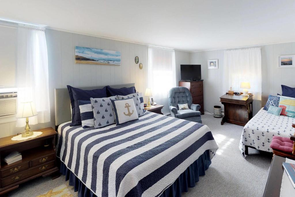 - une chambre avec un lit rayé bleu et blanc et une chaise dans l'établissement SeaWind Guest Studio, à Nauset Heights
