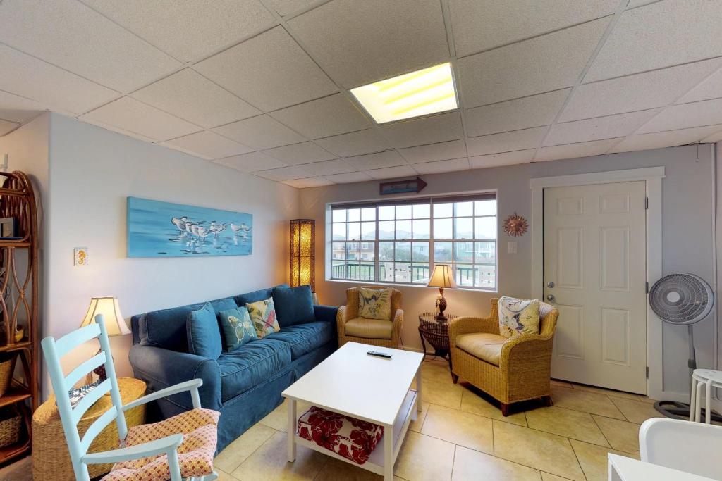 een woonkamer met een blauwe bank en stoelen bij Seaside Pearl in Mustang Beach