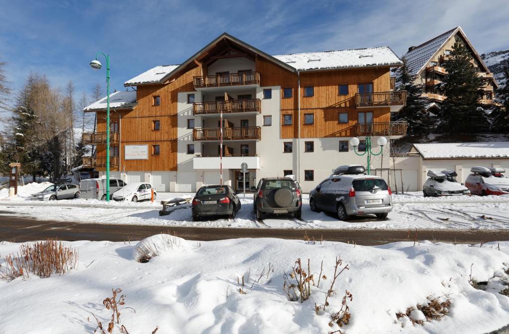 a apartment building with cars parked in the snow at Vacancéole - Au Coeur des Ours in Les Deux Alpes