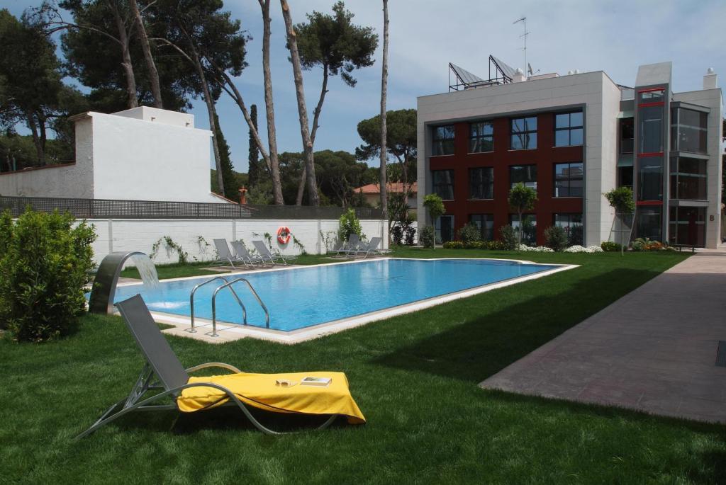a swimming pool in the grass next to a building at Apartamentos Royal Marina Gardens in Castelldefels