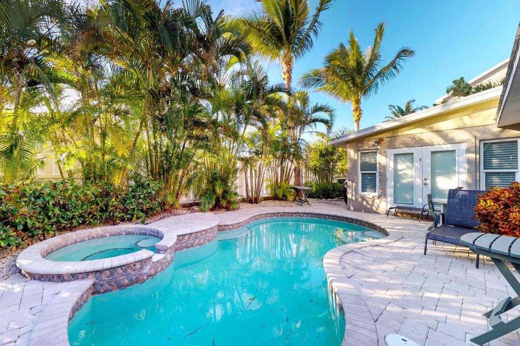 a swimming pool in front of a house with palm trees at Coquina Sands in Holmes Beach