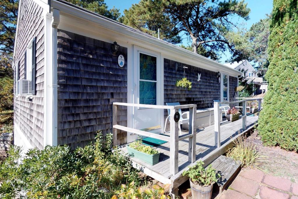 een klein huis met een veranda met planten erop bij Beach Rose Guest Studio in Nauset Heights