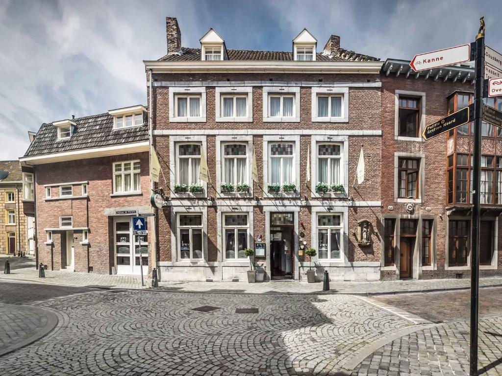 a large brick building on the corner of a street at Hotel Au Quartier in Maastricht