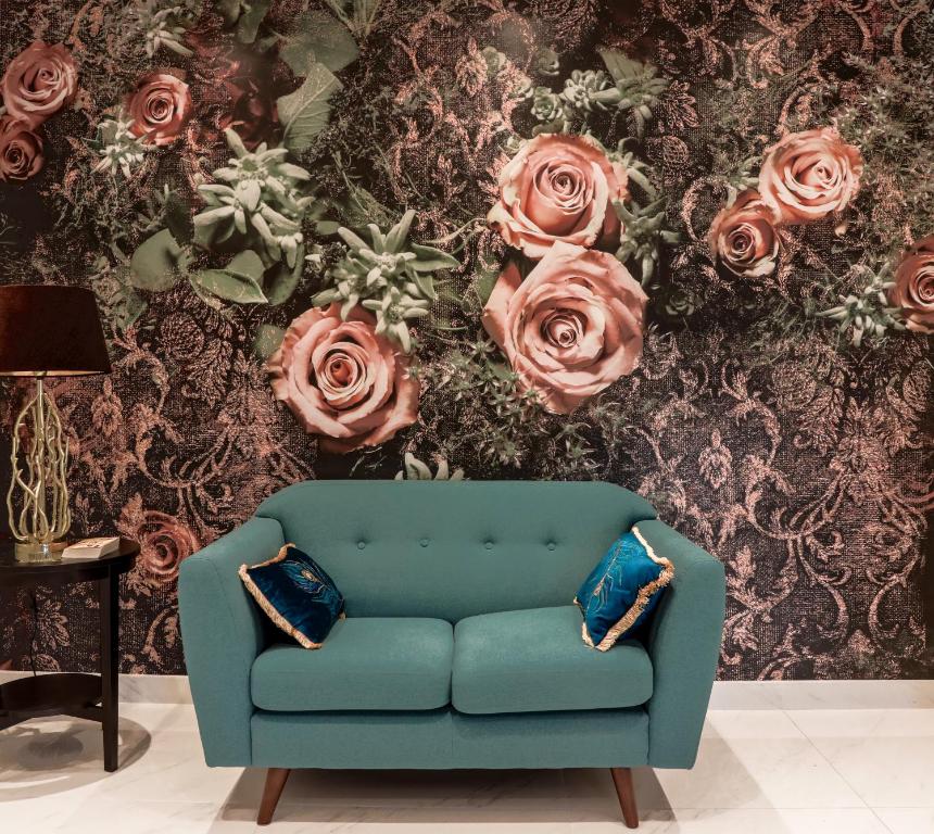 un sofá azul frente a una pared con rosas en Amazing London, en Londres