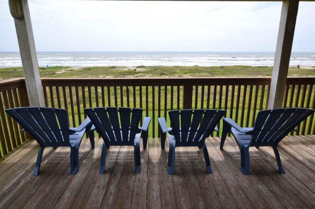 três cadeiras e uma mesa num deque com praia em Sandy Shores em Galveston