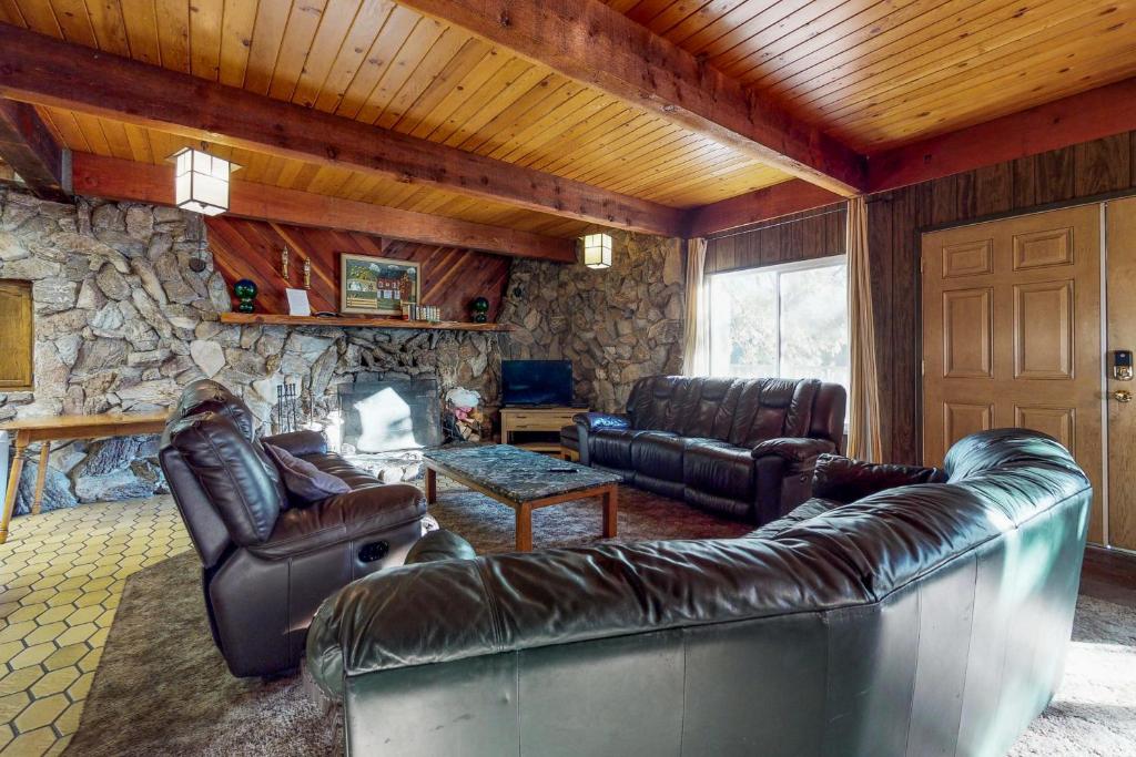 sala de estar con muebles de cuero y pared de piedra. en Pond View Lodge en Shaver Lake