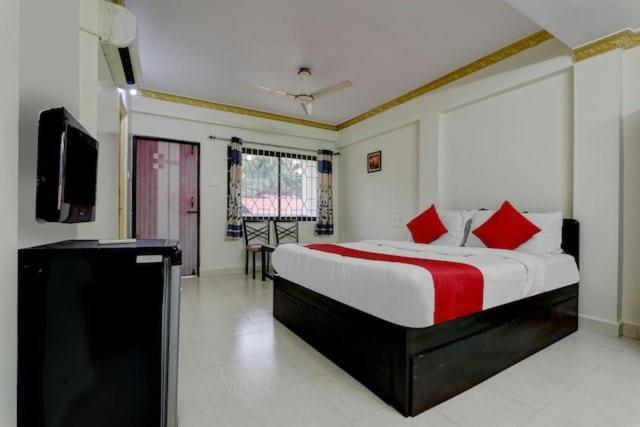 a bedroom with a bed with red pillows and a tv at Roundcube Guest House in Palolem