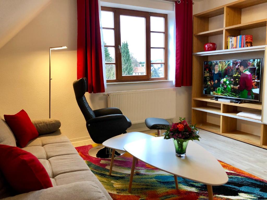 ein Wohnzimmer mit einem Sofa, einem Tisch und einem TV in der Unterkunft Hubertusnest in Bad Berka