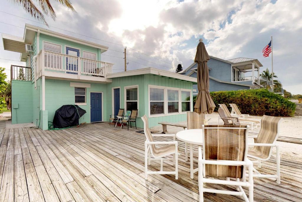 a house with a deck with chairs and an umbrella at Grant's View in Anna Maria