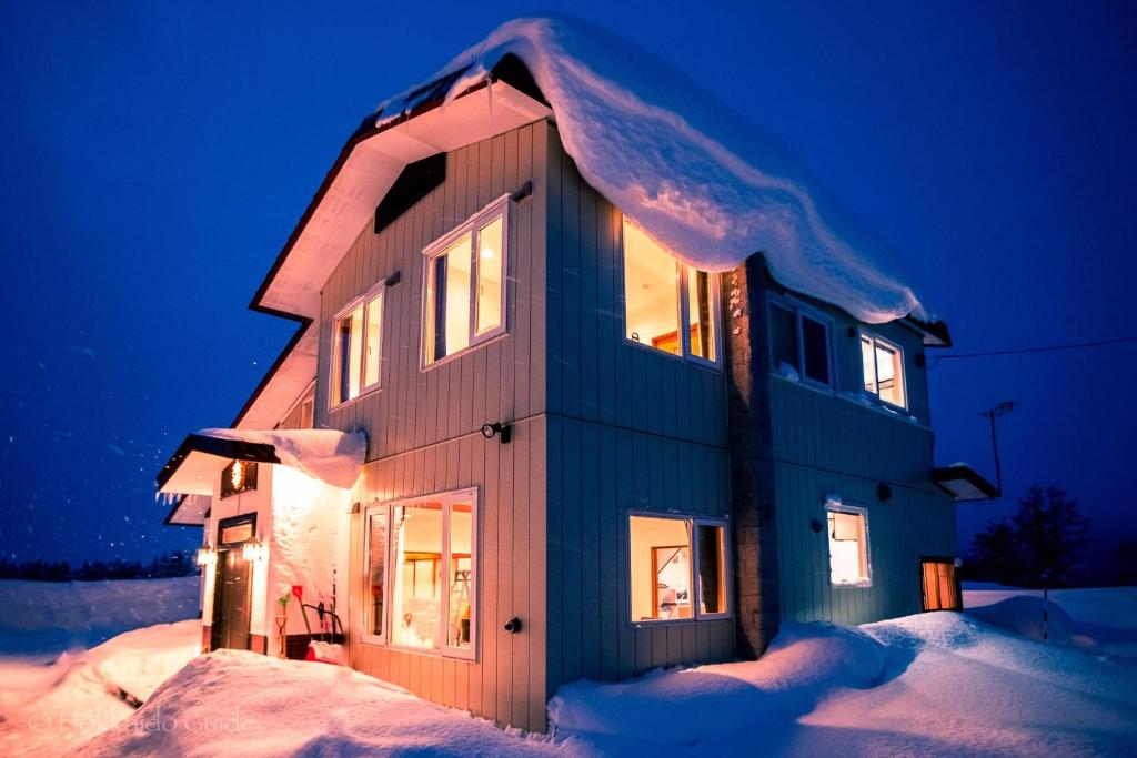 dom pokryty śniegiem w nocy w obiekcie RUSUTSU HOLIDAY CHALET / Vacation STAY 3822 w mieście Makkari