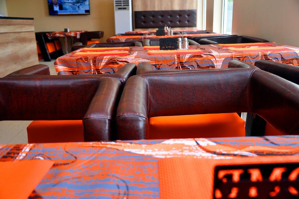 a row of tables and chairs with orange table cloth at Lit Suites in Abuja