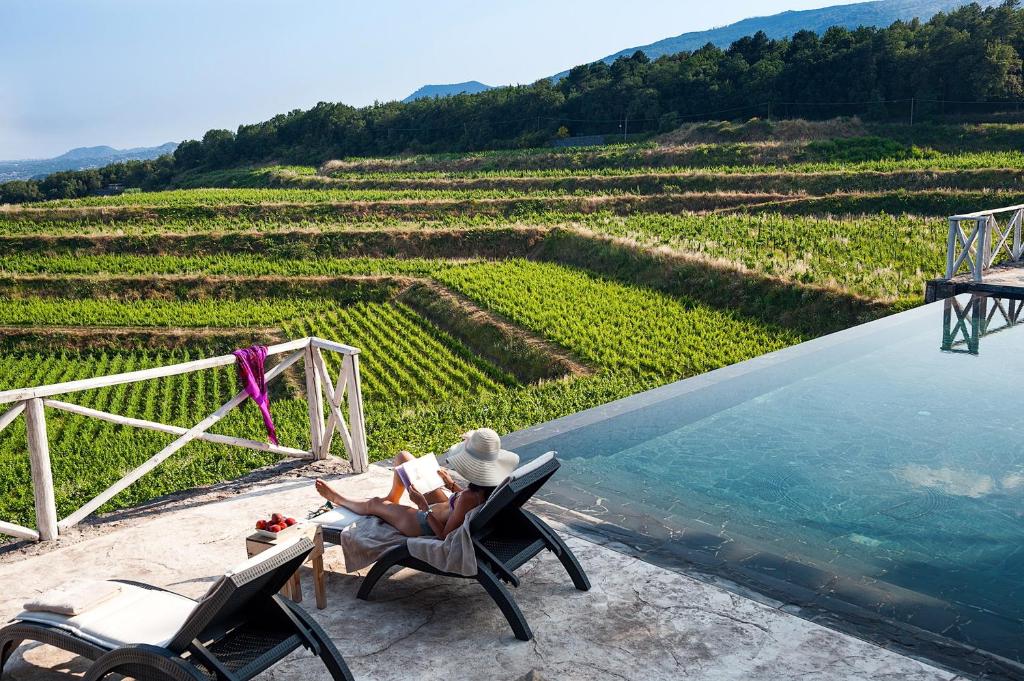 a woman sitting in a chair next to a swimming pool at Wine Resort Villagrande in Milo