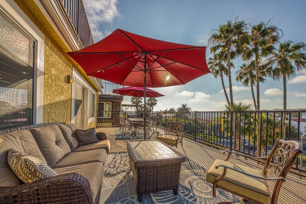 eine Terrasse mit einem Sofa, Stühlen und einem roten Regenschirm in der Unterkunft North Beach D in San Clemente