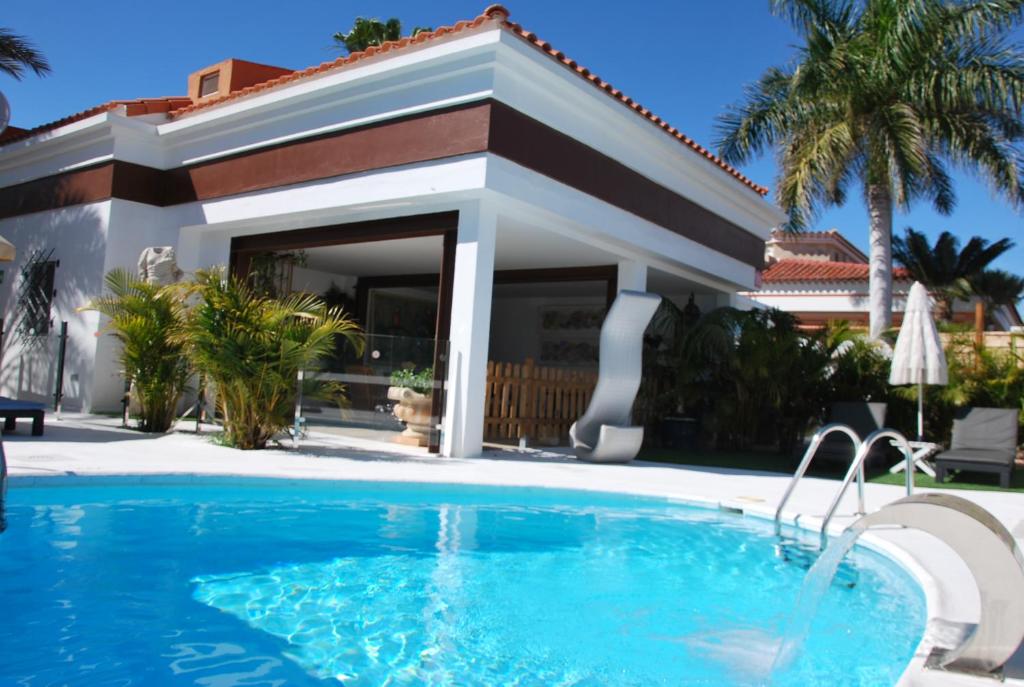 a swimming pool in front of a house at Lacy Golf Apartments in Maspalomas