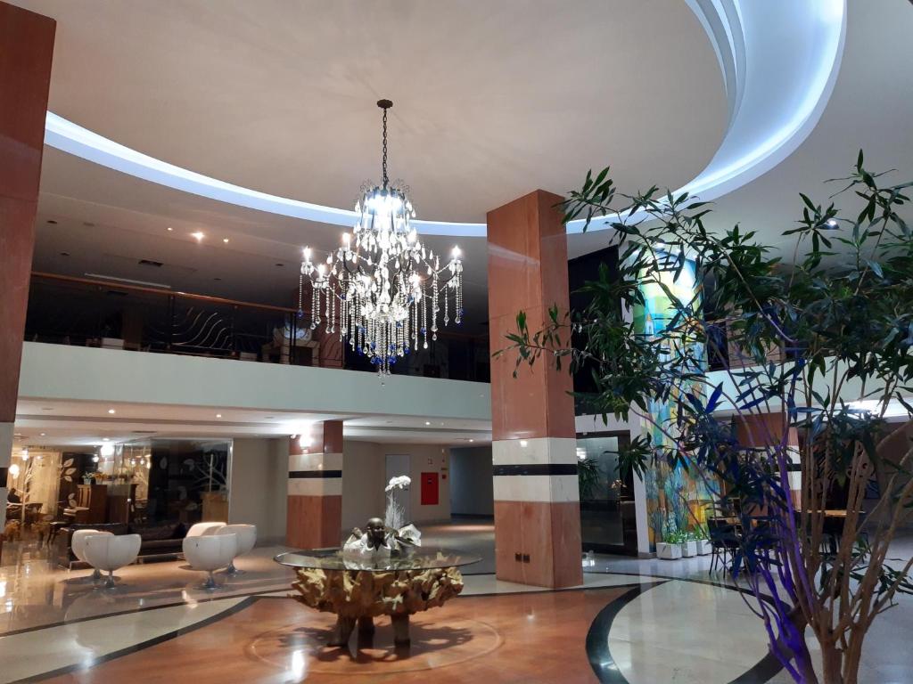a large lobby with a chandelier in a building at Constantino Hotel e Eventos in Juiz de Fora