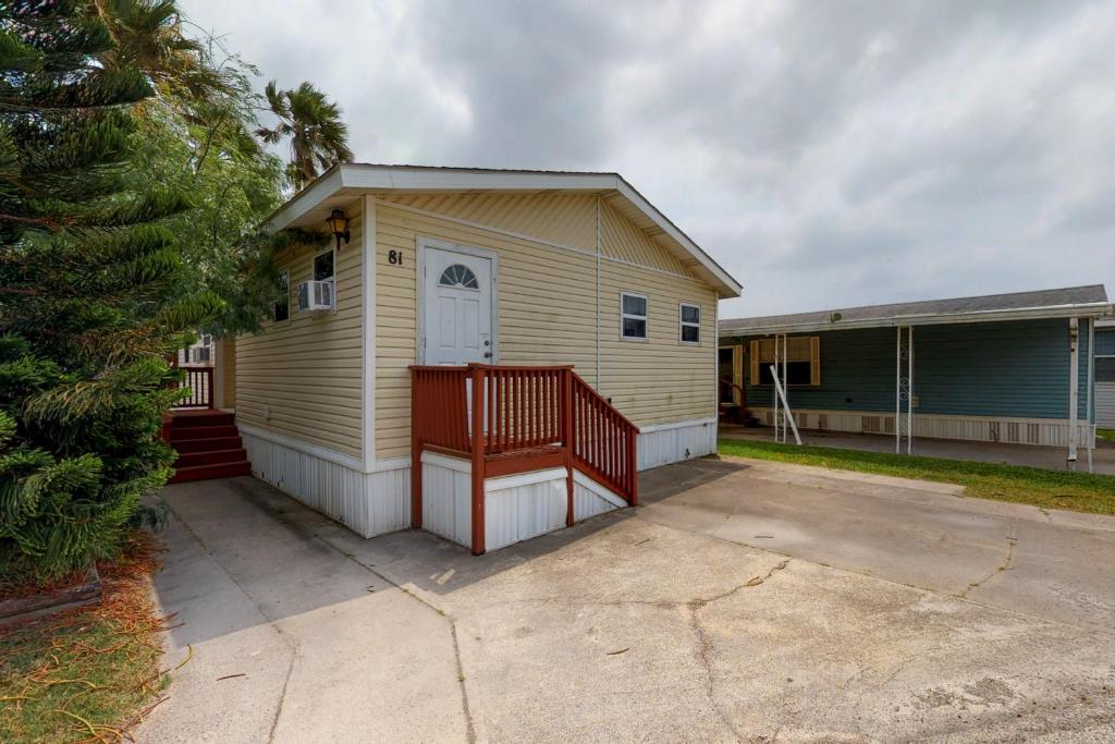 a small yellow house with a porch and a driveway at Long Island Village Unit 081 in Port Isabel