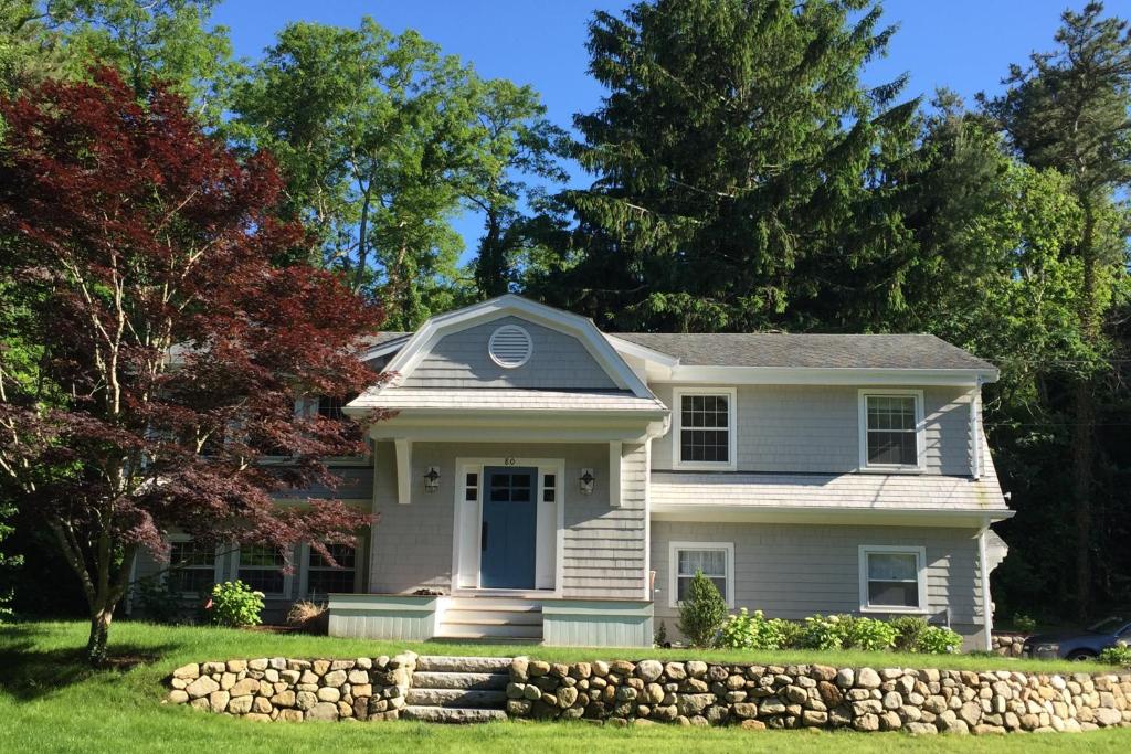 a white house with a stone wall in front of it at The Happy Place in Falmouth