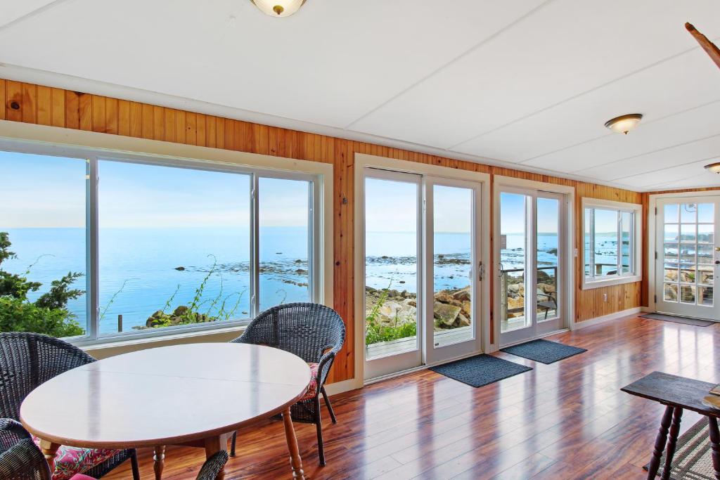 una sala da pranzo con tavolo, sedie e finestre di Retreat Cottage a Plymouth