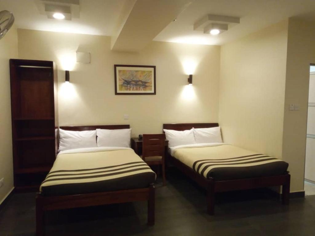 Habitación con 2 camas en una habitación de hotel en Shangri-La Fortune Hotel en Kampala
