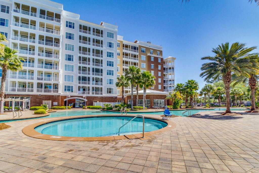 a pool in front of a large building with palm trees at Reflections At Bay Point II in Panama City Beach