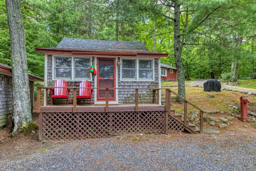 una pequeña casa con 2 sillas rojas en un porche en Toddy Pond Jack, en Orland
