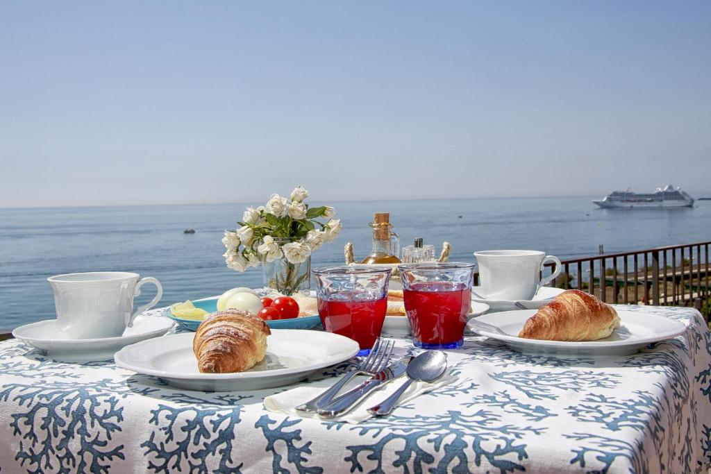 a table with croissants and pastries on it with the ocean at B&B Sottocoperta in Taormina