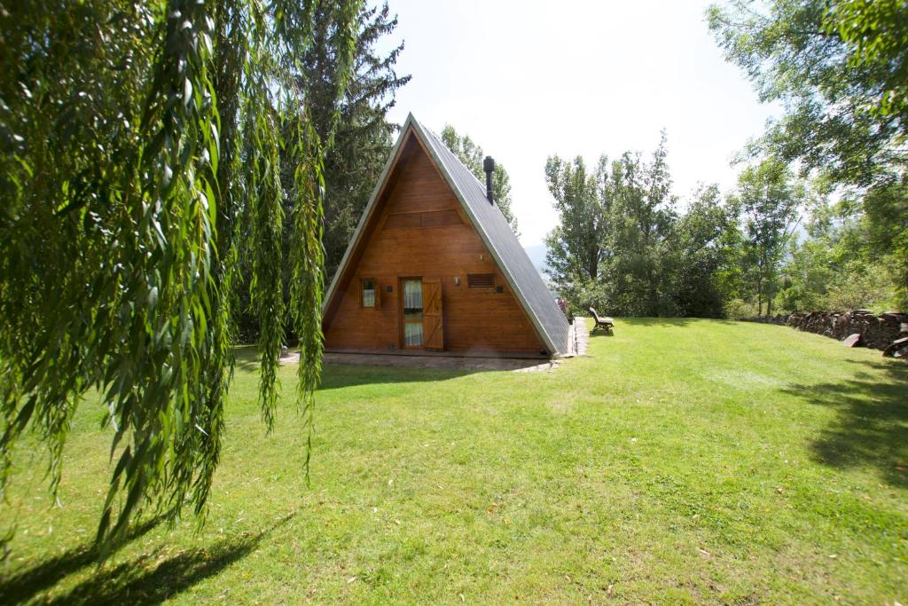 a small wooden cabin in a field with a grass yard at La cabaña de Ger in Ger