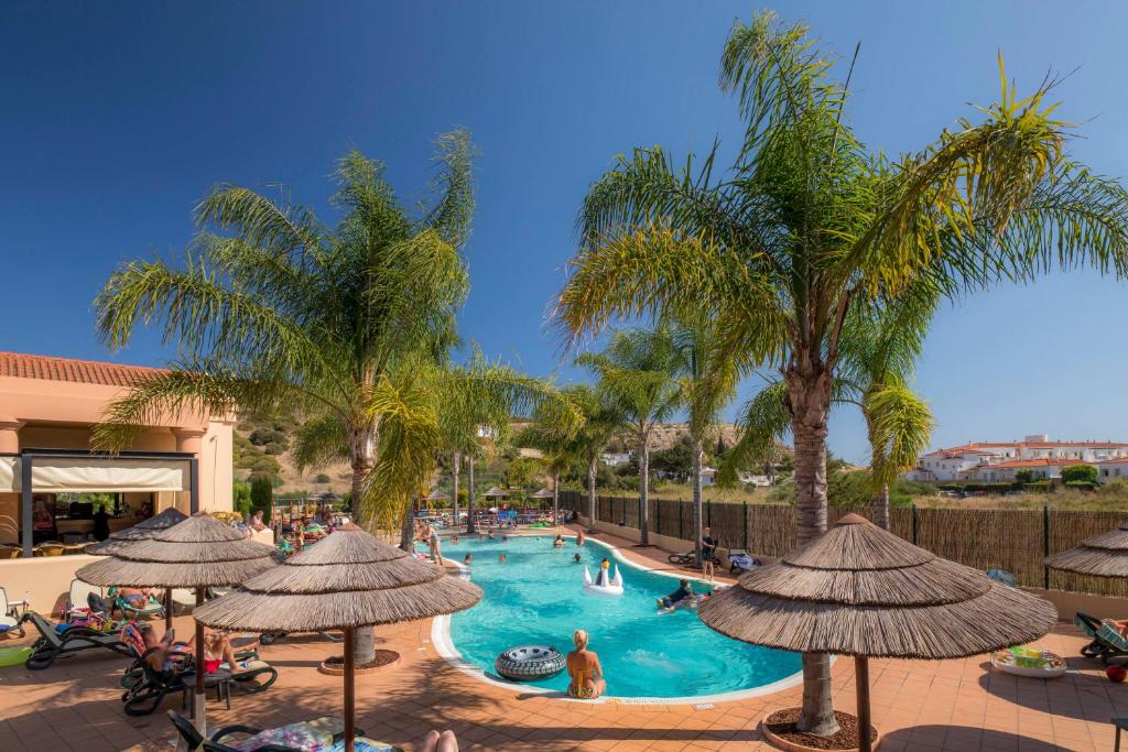 een zwembad in een resort met palmbomen en mensen erin bij Luz casas- BayLuz apart,pool,beach, tennis, wifi,aircon in Luz