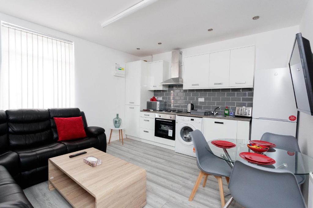 a living room with a couch and a table and a kitchen at Calvin House Apartments in Leeds