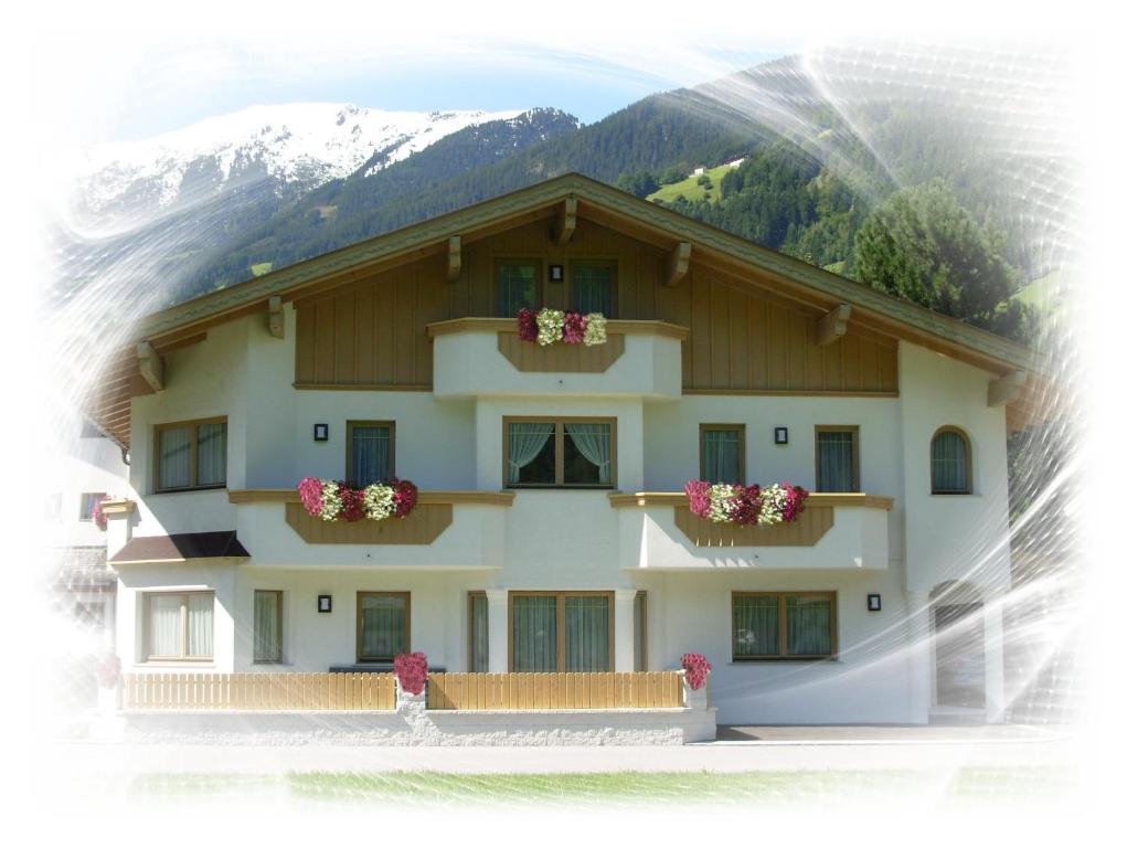 a building with flowers in the windows and mountains at Appartement Geisler in Zell am Ziller