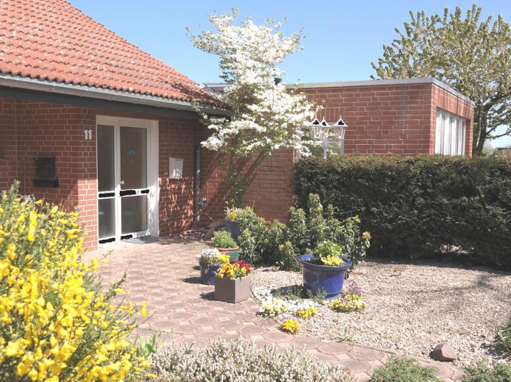 ein Backsteinhaus mit einem Garten mit Blumen davor in der Unterkunft APPartementWESTiNGhaus in Edemissen