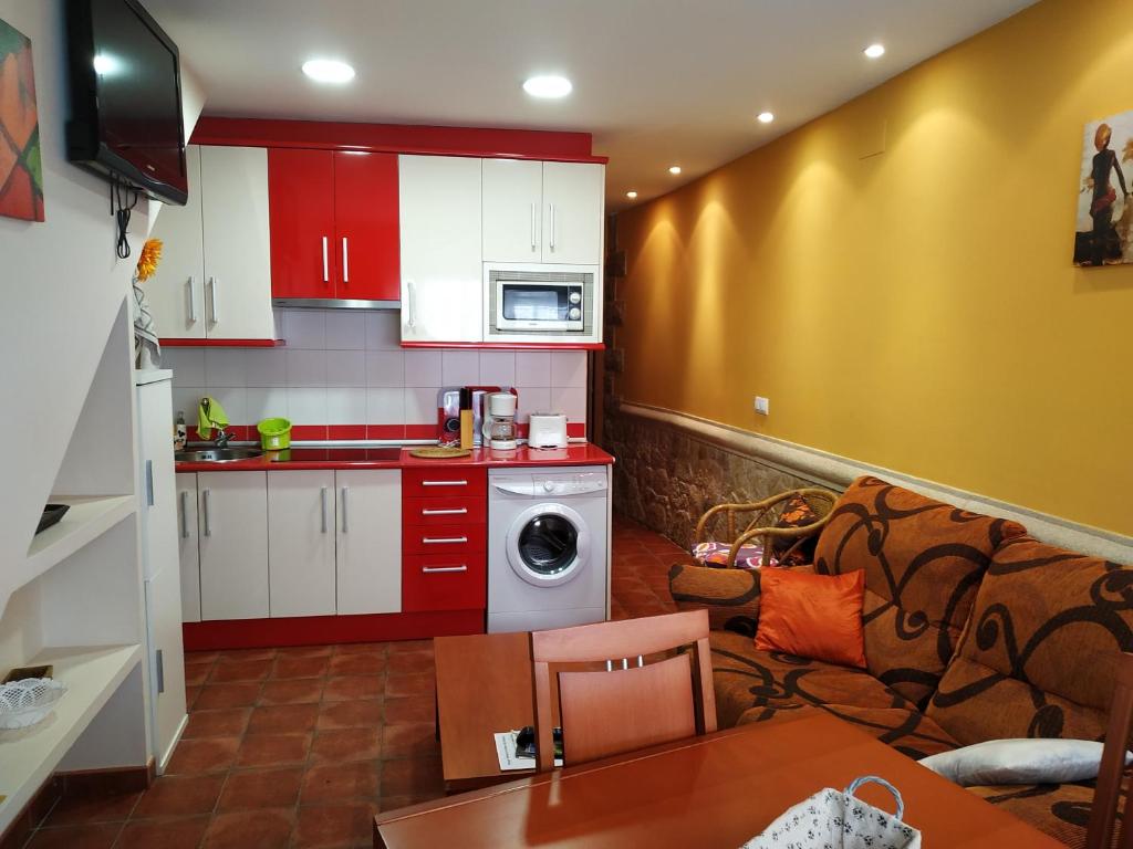 kuchnia z czerwonymi szafkami i salon w obiekcie Apartamentos Arribes la Corredera w mieście Aldeadávila de la Ribera
