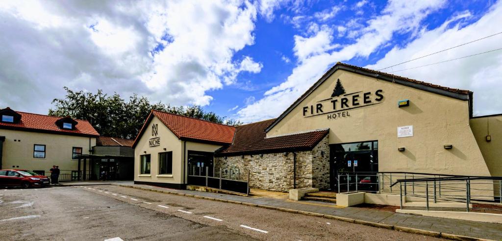 un bâtiment avec des arbres inscrits sur son côté dans l'établissement Fir Trees Hotel, à Strabane