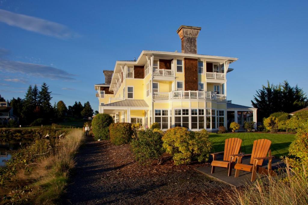 Una gran casa blanca con dos sillas delante. en Resort at Port Ludlow en Port Ludlow