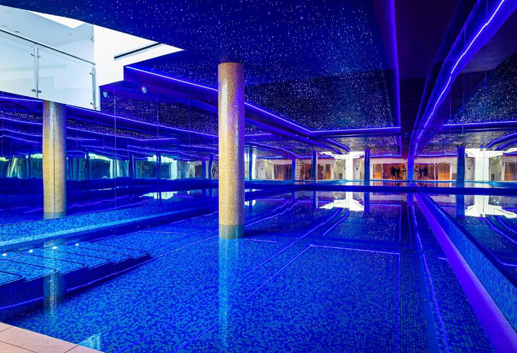 einem Pool in einem Gebäude mit lila Beleuchtung in der Unterkunft Atrium Hotel Heathrow in Hillingdon