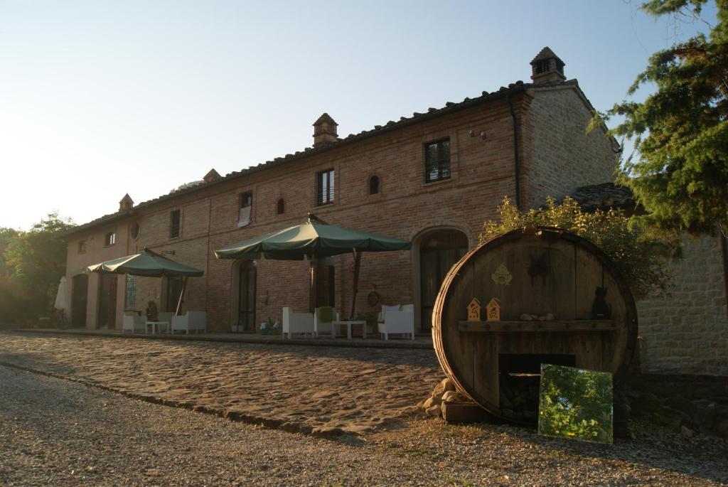 a building with a barrel in front of a house at AGRITURISMO SAN MARTINO in Monte San Martino