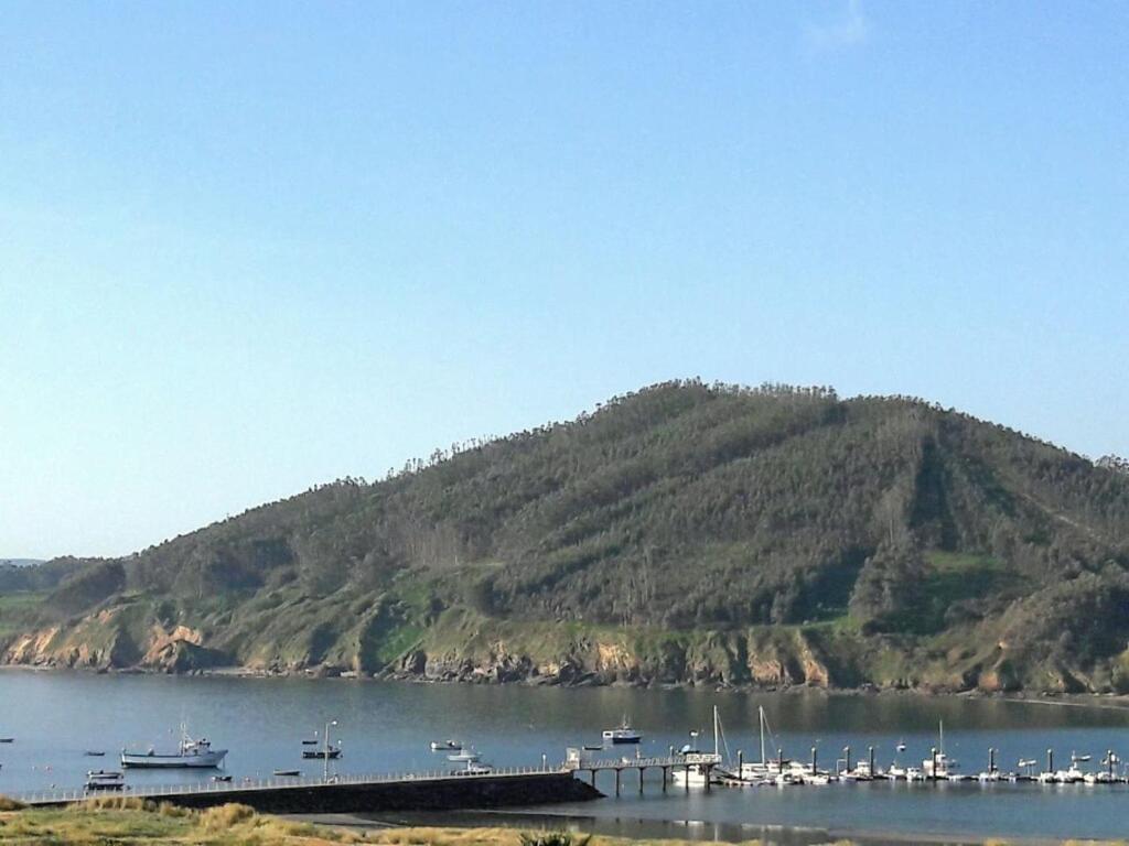 a mountain with a bunch of boats in the water at 1ª LÍNEA DE PLAYA, VISTAS AL MAR Y MUY CÉNTRICO. in Cariño