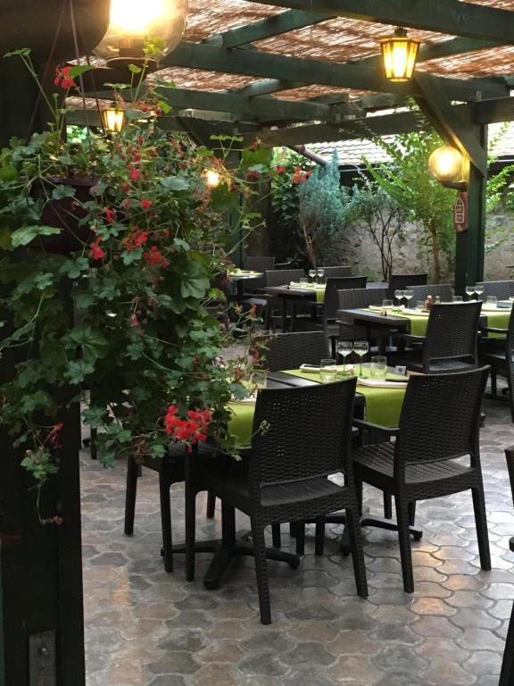 a patio with tables and chairs and red flowers at Auberge du Tisserand in Gommersdorf