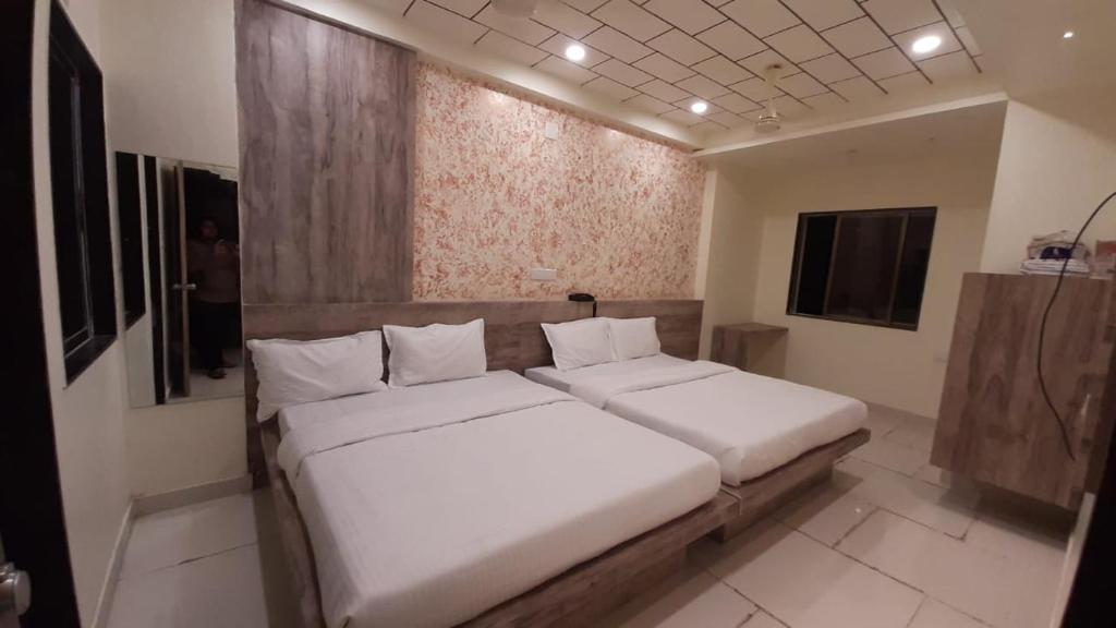 a bedroom with a large bed with white sheets at Hotel Dwarawati in Dwarka